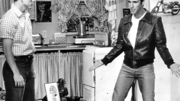 Black and white still from Happy Days showing Fonzie and Richie standing in Fonzie's garage apartment.