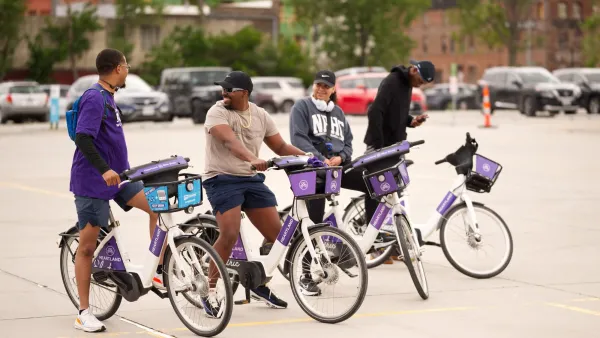 Four people standing on Heartland bike share bikes and talking to each other.