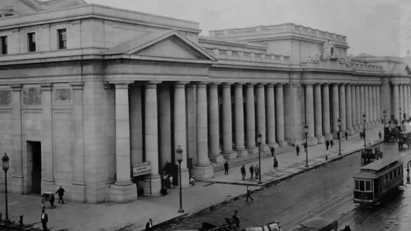 An image of historic Penn Station when it was first built in 1910, viewed from the outside with people, carriages, and streetcars passing by.