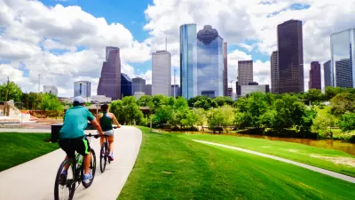Two people on a bike trail with downtown Houston in the background