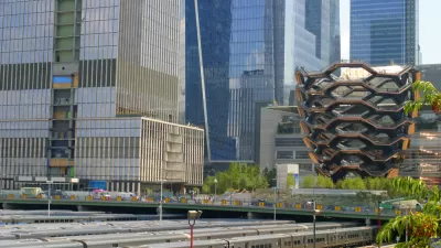 Numerous trains are lined up at the Hudson Yards train depot with the fancy architecture of Hudson Yards in the background.
