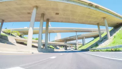 An image taken from the point of view of a driver on a mostly empty freeway, with large overpasses overhead.