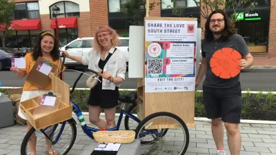 A group of people gather around an information booth to share ideas about the future of South Street in Philadelphia.