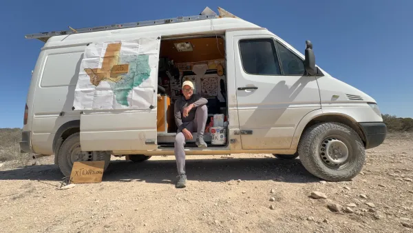 Charles Gandy sitting in the open side door of a white van with map of Texas inside door.