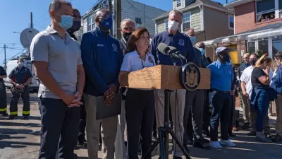 New York politicians, including Governor Kathy Hochul and Mayor Bill de Blasio, gather in front of microphones for a press conference.