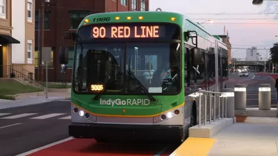 Green rapid transit bus pulled into station in dedicated lane.