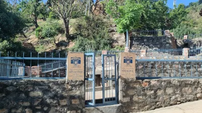 Historic stone structure surrounding natural spring in India with plaques.