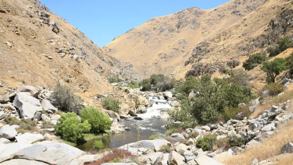 The Kern River passes through a steep river canyon filled with jagged rocks and surrounded by hills of golden grass. 