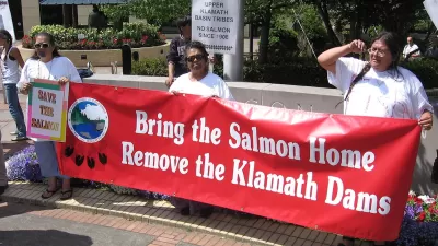 Native demonstrators hold a red banner reading "Bring the salmon home - Remove the Klamath Dams."