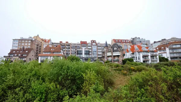 Belgian town with traditional architecture on hillside.