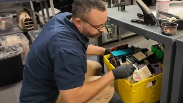 Man in blue shirt looking into yellow lost and found bin at Los Angeles Metro office.