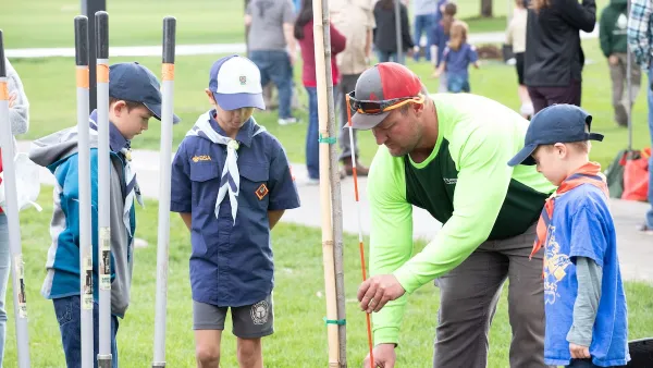 Adults and children planting trees during Arbor Day event in Lakewood, Colorado.