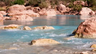 A river runs blue through the red rocks of the desert.