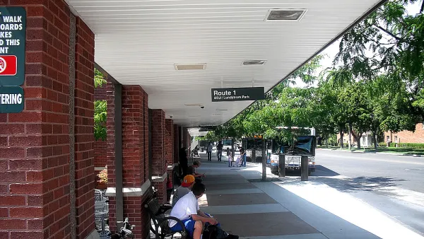 People waiting under covered brick bus shelter in Logan, Utah.