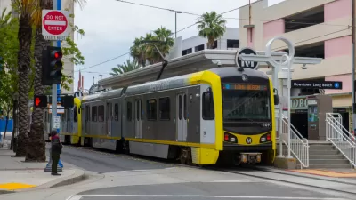 A light rail train waits at the Downtown Long Beach station with a sign that reads “Long Beach” to declare its route to riders.