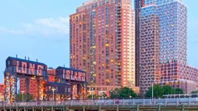 A photo of a bridge reading Long Island City in front of high-rise buildings glittering in a sunset.