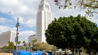 A group of tents line a street in front of Los Angeles City Hall.
