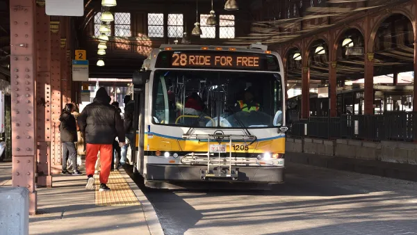 White and yellow MBTA bus with "28 Ride for free" on the marquee stopped at Nubian Station under ornate high roof.