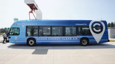 Blue electric MCTS bus sits at a charging station