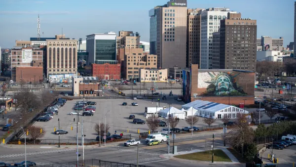 Parking lot in downtown Detroit, future home of university of michigan center for innovation, with mural of Statue of Liberty's head on building behind lot.