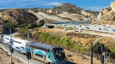 Silver and white Metrolink commuter train passing through Newhall Pass with desert mountains in background in Antelope Valley, California.