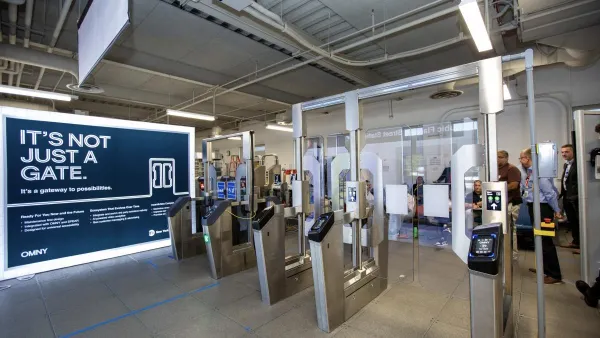 New fare gates with clear panels with people standing behind them in NYC subway station.