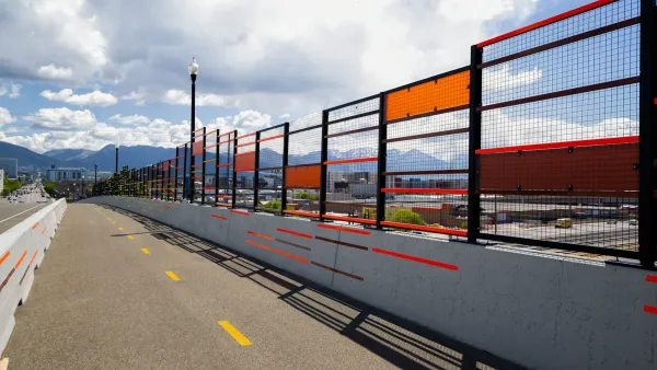 A bike lane protected by concrete barrier on bridge in Salt Lake City with colorful public art running alongside.