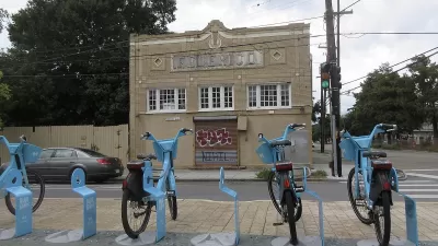Row of blue Blue Bikes bike share bikes at docked station on sidewalk in New Orleans, Louisiana.