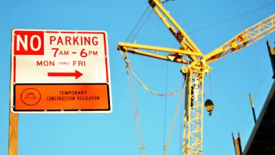A sign reads “No Parking” for temporary construction, with a construction crane in the background.