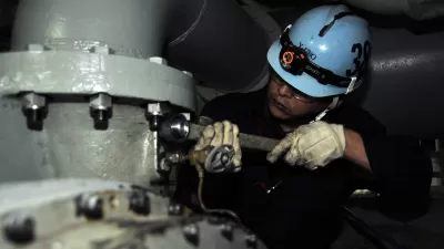 Japanese shipyard worker performs preservation work on ships air conditioning system.