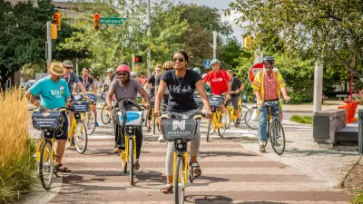 Group of people riding Pacers Bikeshare bikes on a tree-lined paved path.