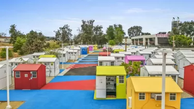 Multicolored tiny homes for temporary shelter in complex adjacent to freeway overpass in Los Angeles, California.