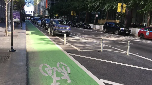 Green painted bike lane protected by rown of parking.