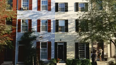 A family exits from a rowhouse. Picture is identifiably from the 1980s based on the clothing fashion of the family.