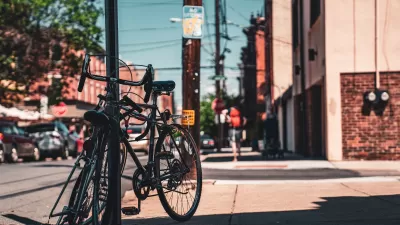 A pair of bikes are leaning against a street sign on an urban street in Philadelphia.