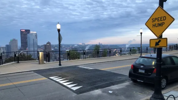 Wide speed hump on Pittsburgh bridge with yellow Speed Hump sign on sidewalk.