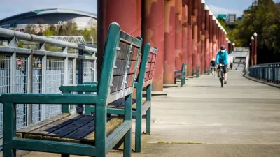 A single bike rider wearing a mask rides along a waterfront in Portland, Oregon.