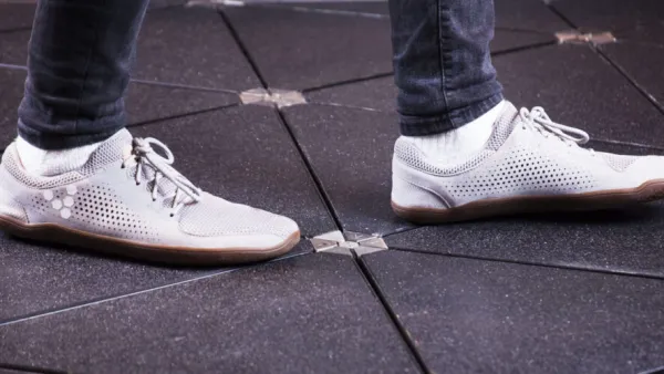 Close-up of white sneakers walking on solar-powered sidewalk panels.