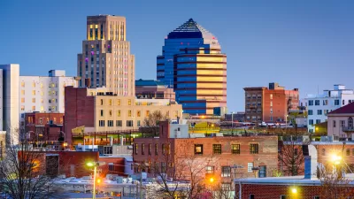 An image of the Raleigh skyline, with older residential buildings in the foreground and taller commercial buildings in the background.