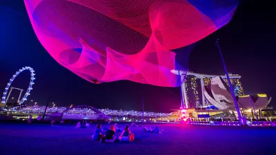 Pink light art installation above public plaza in Singapore by Janet Echelman.