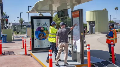Two men looking at wayfinding sign on prototype bus shelter in North Hollywood, California.