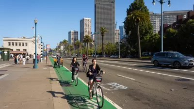 A group of cyclists rides on a green painted bike line on the Embarcadero in Sa Francisco.