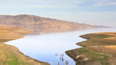 A barren landscape surrounds a reservoir well below its capacity.