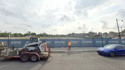 Google Street View of empty construction site with blue construction fence
