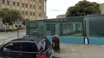 Google street view of tiny home village behind see-through green fence at 33 Gough St. in San Francisco with brick building in background