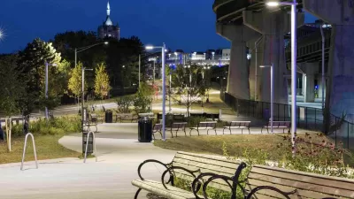 Benches along lit paved bike trail adjacent to freeway overpass in Albany, New York