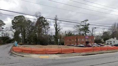 Vacant corner lot in Atlanta, Georgia surrounded with low orange plastic construction fencing.