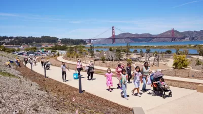 People walking on a concrete pathway at Presidio Tunnel Tops with the Golden Gate Bridge in the background