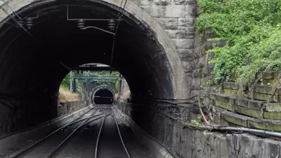 View into gray stone train tunnel with visible opening on other side