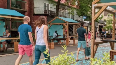 Pedestrians walk down car-free Mont-Royal Avenue next to green outdoor dining kiosks in Montreal, Canada